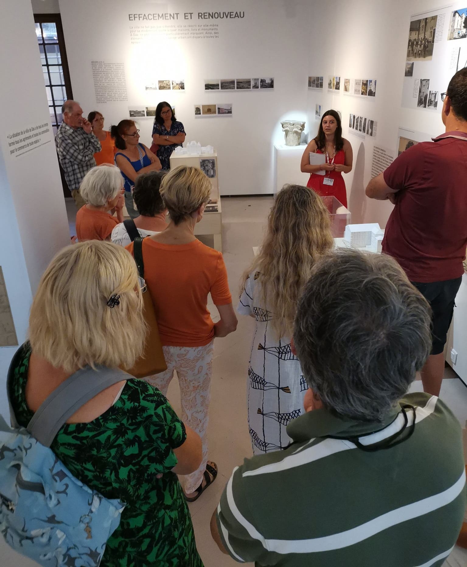 Photographie d'un groupe d'adultes en train d'écouter une guide interprétant les œuvres du musée dans le cadre d'une visite commentée